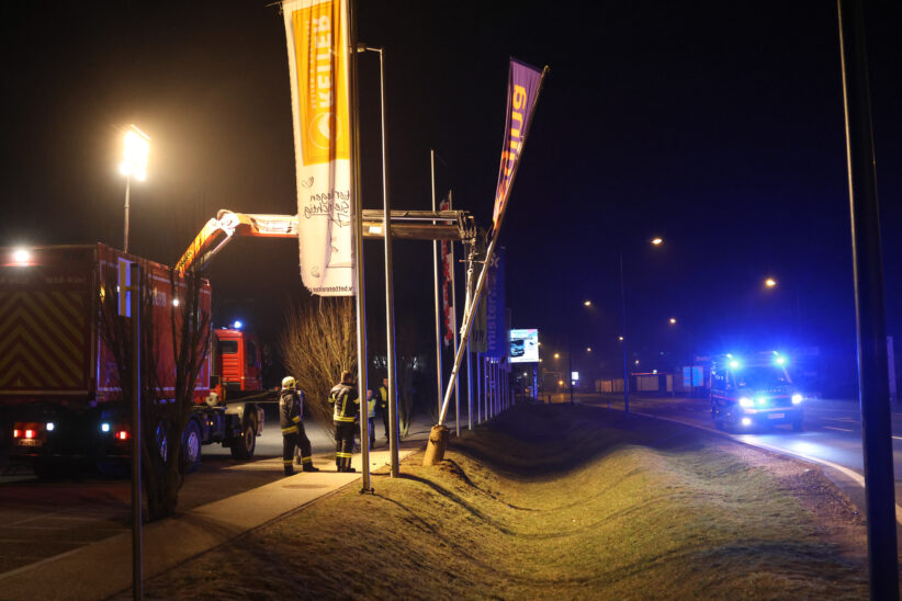 Unfall in Wels-Waidhausen: Schrägstehenden Fahnenmast mit Kran der Feuerwehr aus dem Boden gezupft